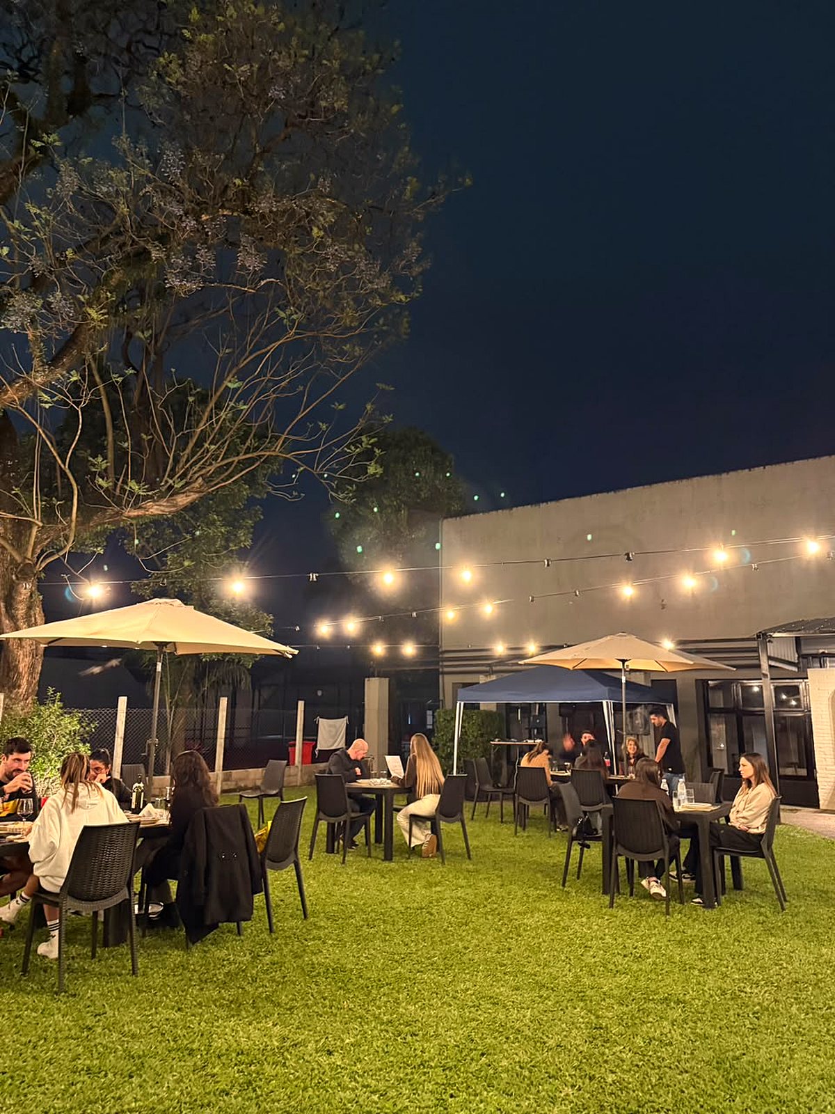 Patio de Fagú Resto en Boyacá 54 de noche, con luces y mesas